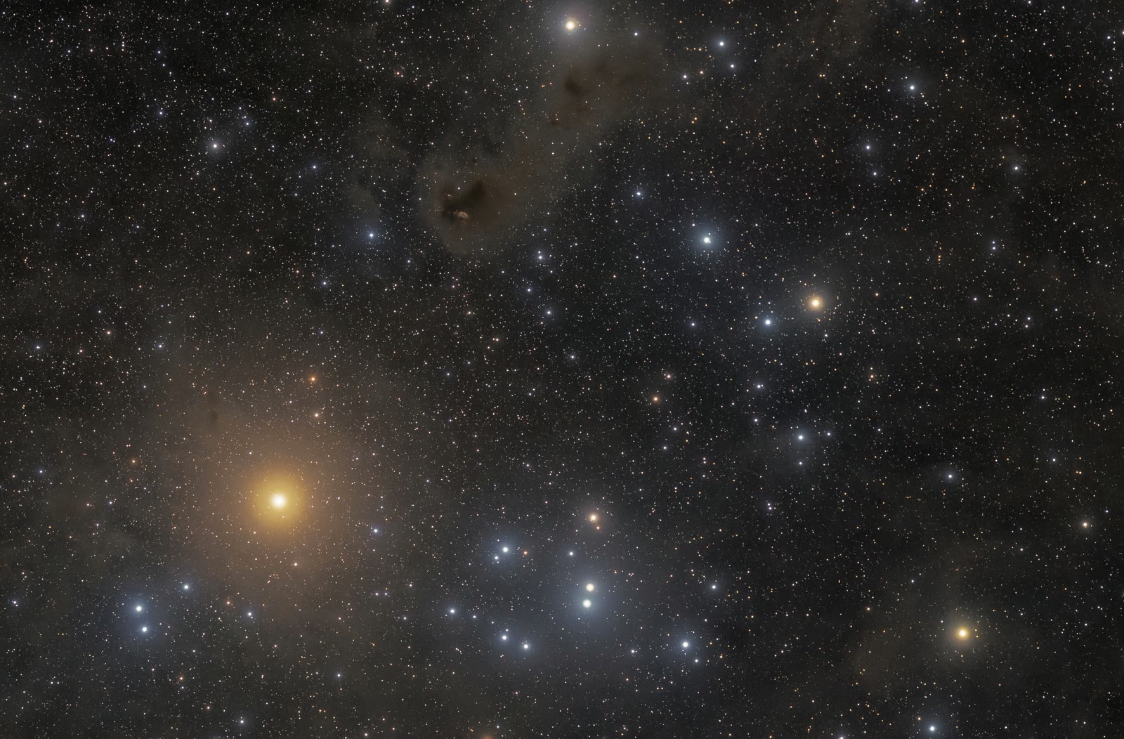 Aldebaran is the bright orange star at left, set in front of the Hyades star cluster whose scattered blue-white stars fill the rest of the frame.