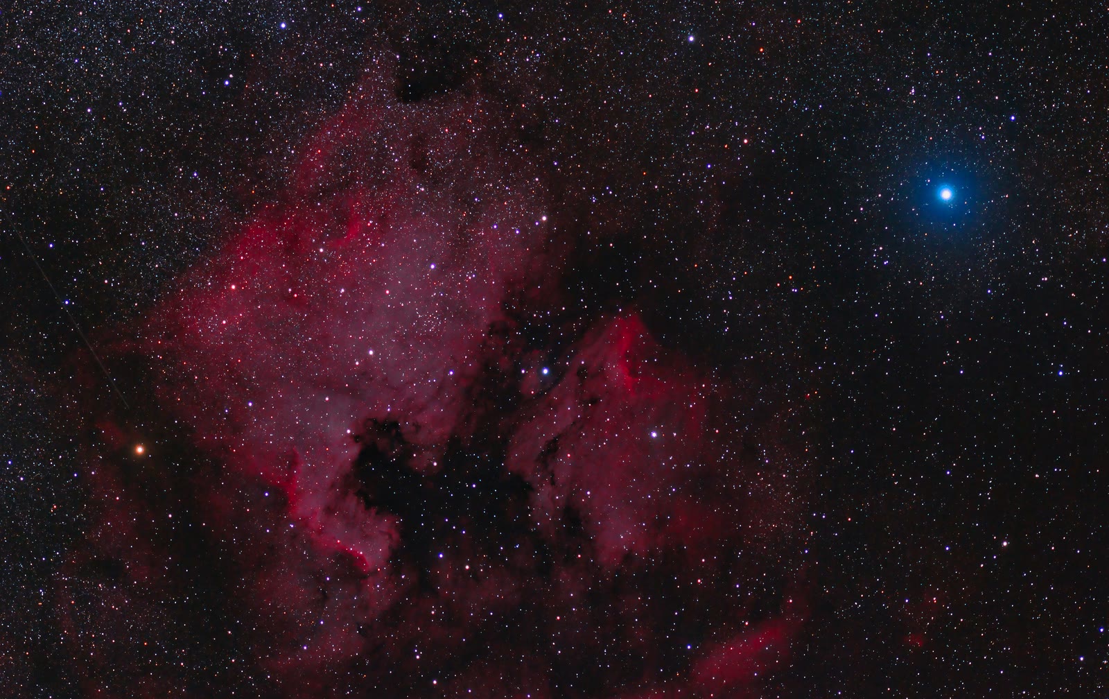 Deneb is the brilliant blue-white star at upper right, beside the red glow of the North America Nebula (left) and the Pelican Nebula (centre) in Cygnus.
